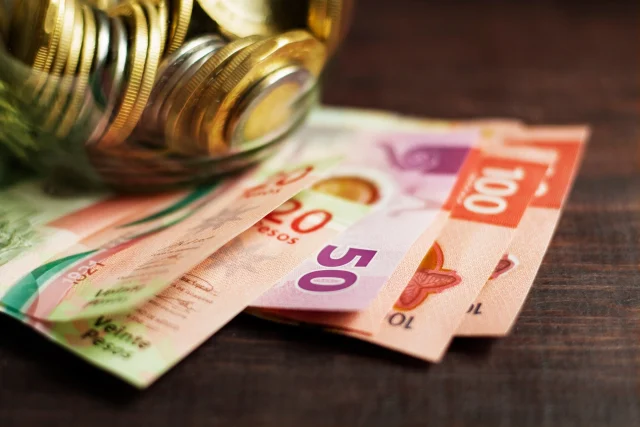 Billetes mexicanos de 20, 50 y 100 pesos debajo de una alcancía de vidrio lleno de monedas; Derecho fiscal.